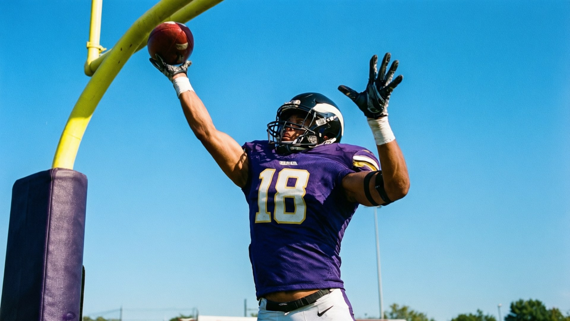 Wide receiver salta in alto per prendere un football nella end zone.