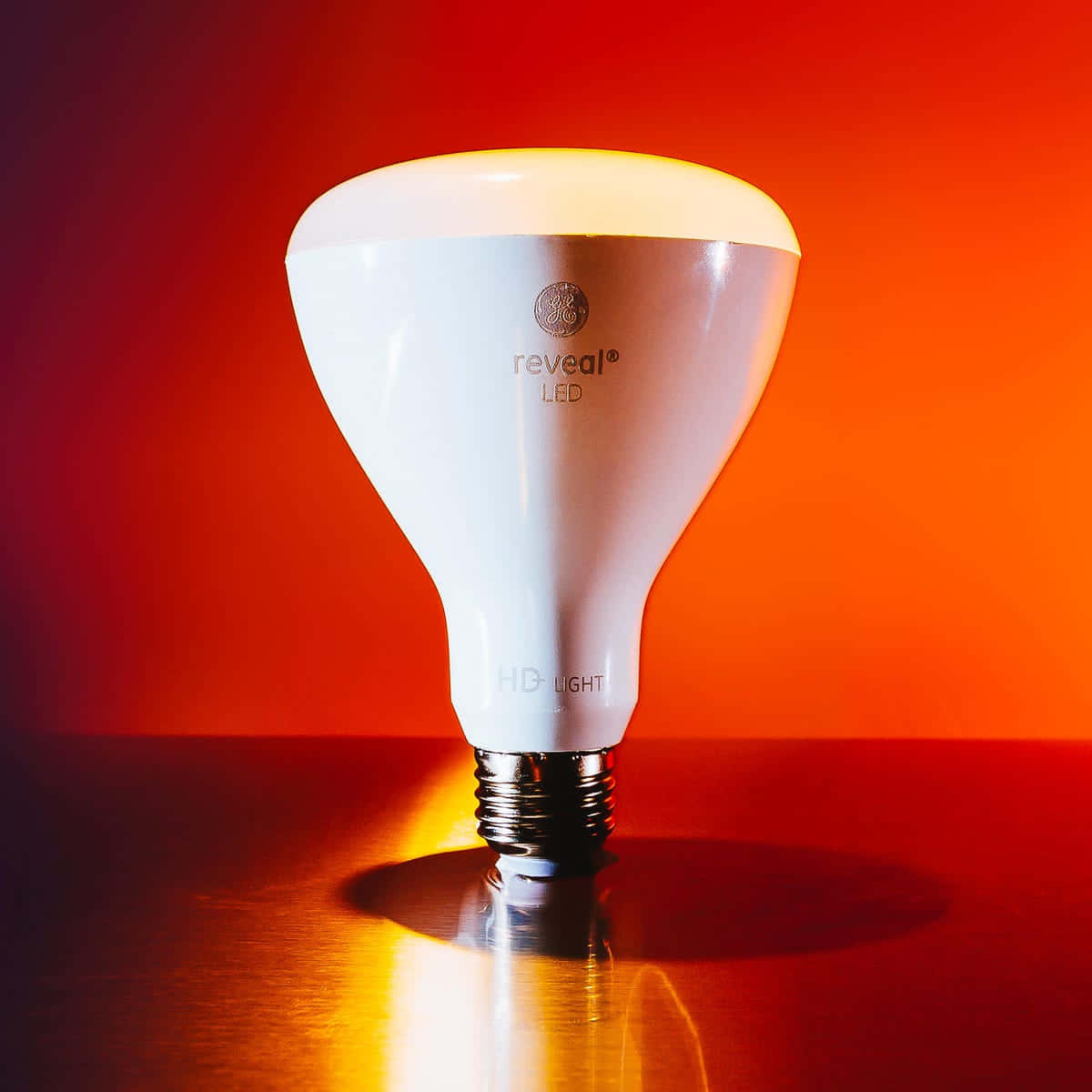 A Light Bulb Is Sitting On A Table In Front Of A Red Background