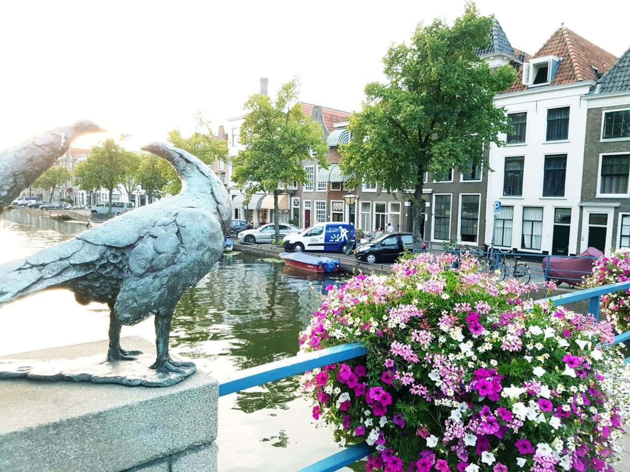 Leiden Canal Viewwith Bird Statueand Flowers Wallpaper