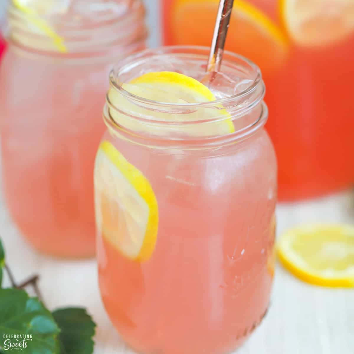 A Pitcher Of Pink Lemonade With A Straw And Lemons