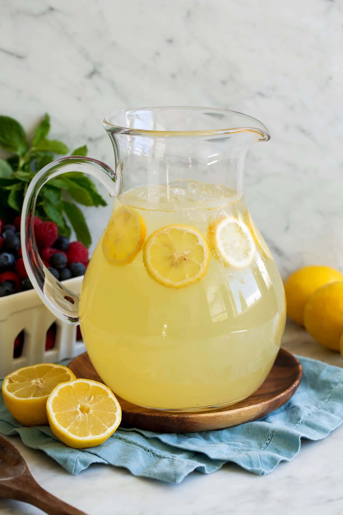 A Pitcher Of Lemonade With Lemon Slices And Berries