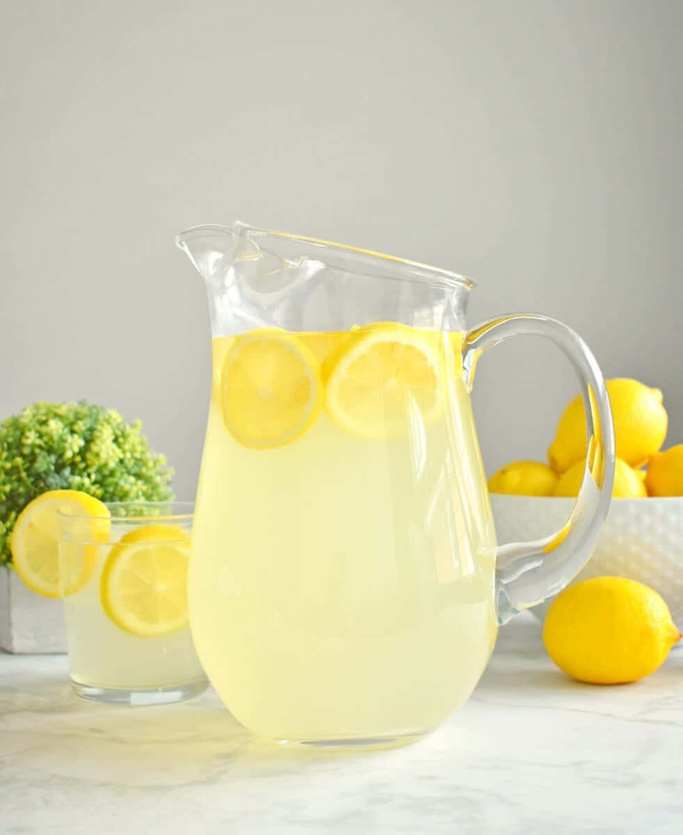 A Pitcher Of Lemonade With Lemons And A Glass Of Water
