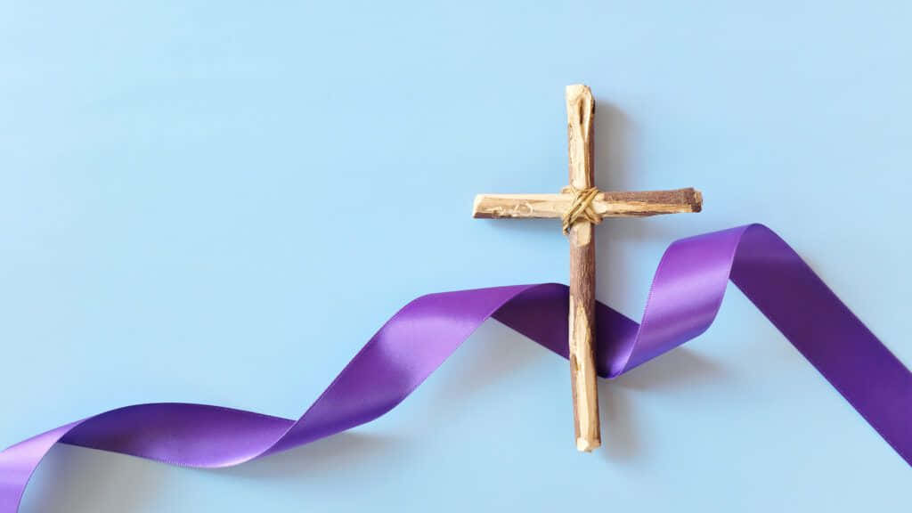 A Wooden Cross On A Purple Ribbon