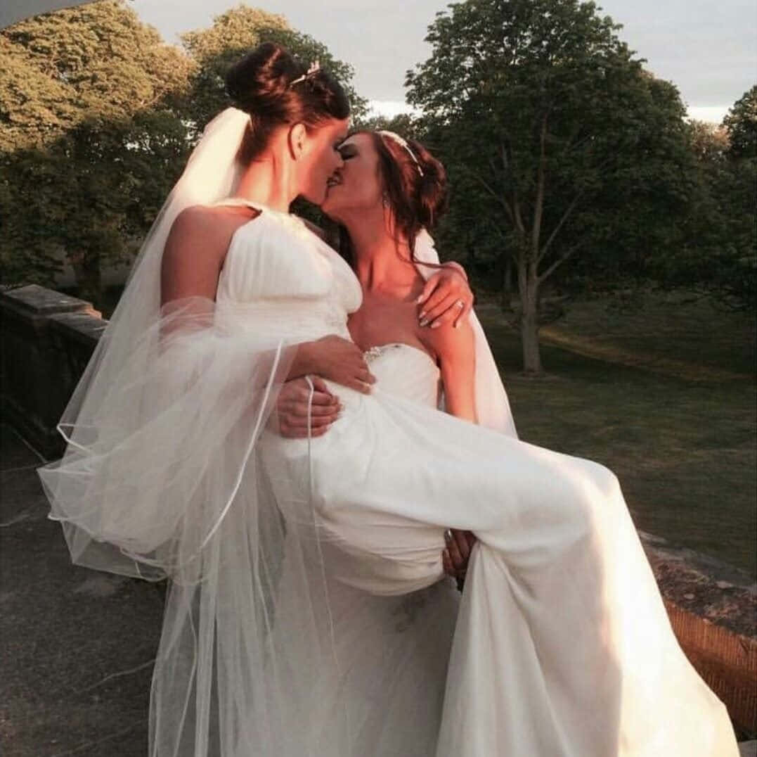 Two Brides Kissing On A Balcony