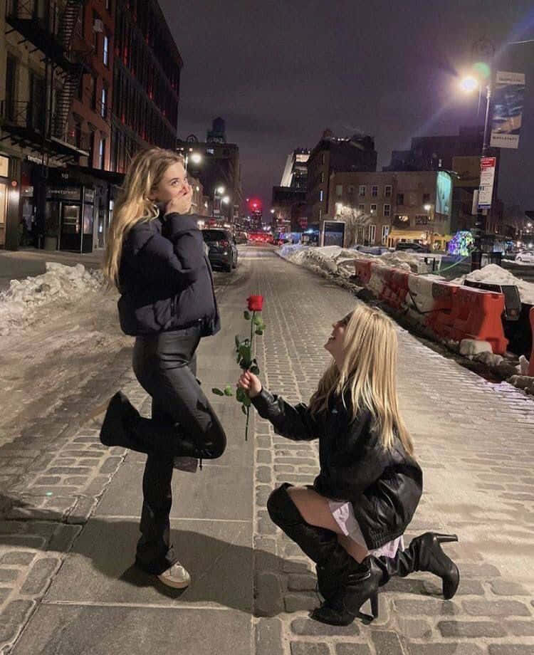 Two Women Are Kneeling On A Snowy Street