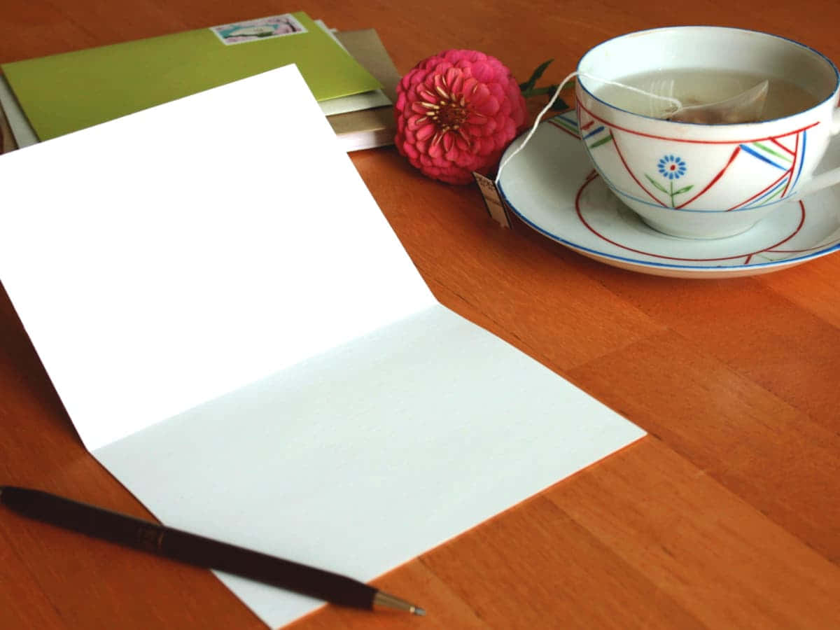 A Cup Of Tea And A Notepad On A Table