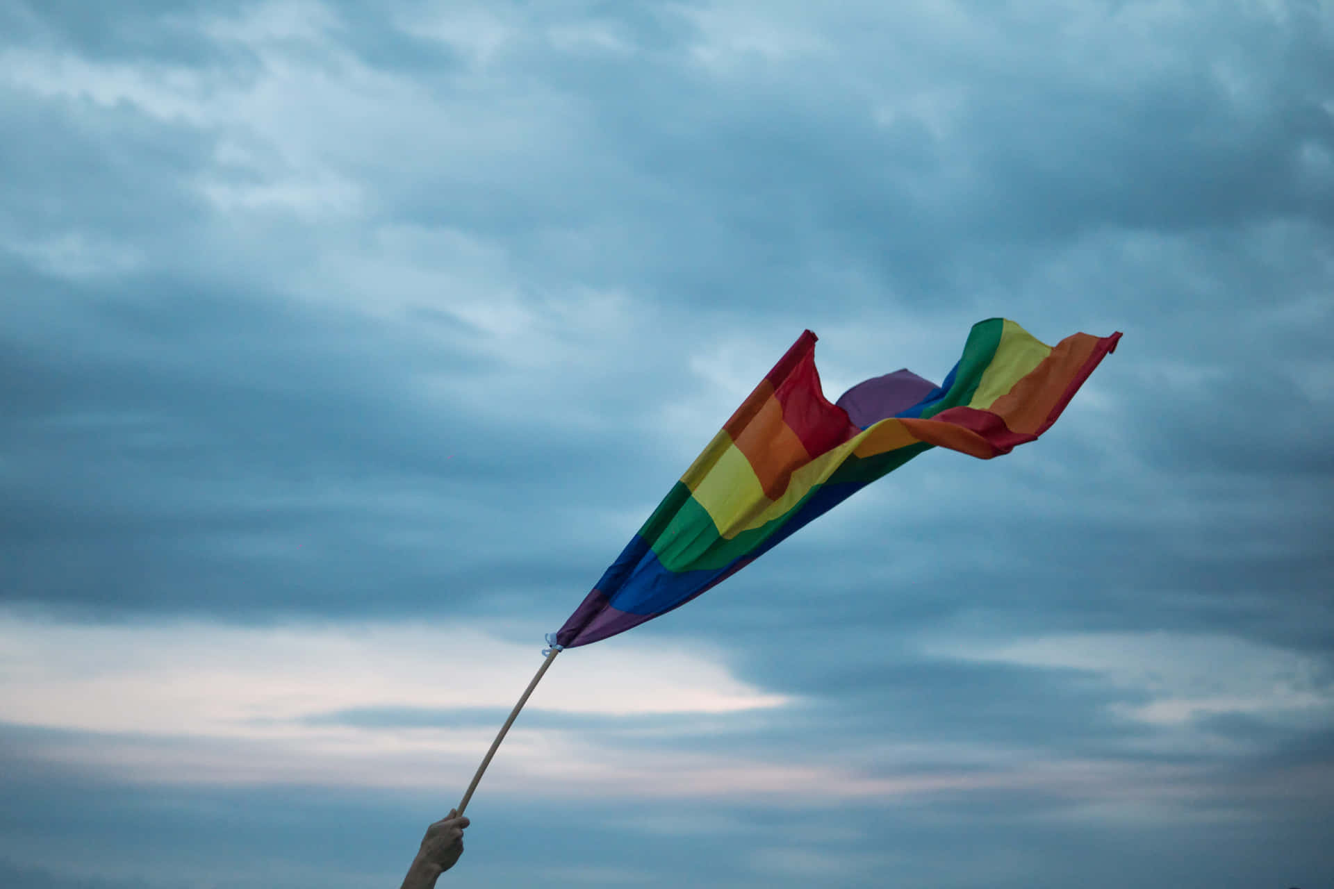 A Rainbow Flag Is Being Held Up By A Person Wallpaper
