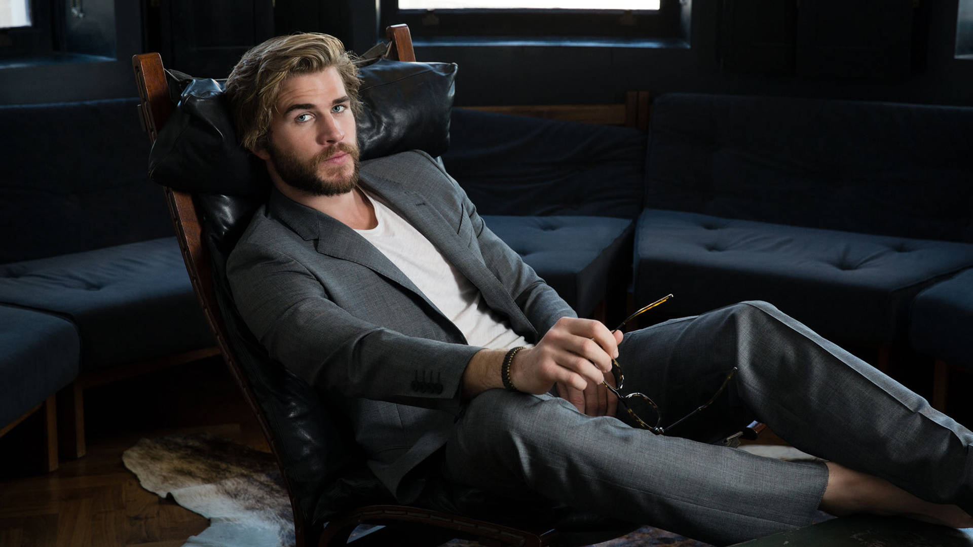 Liam Hemsworth Sitting On Black Couch Wallpaper