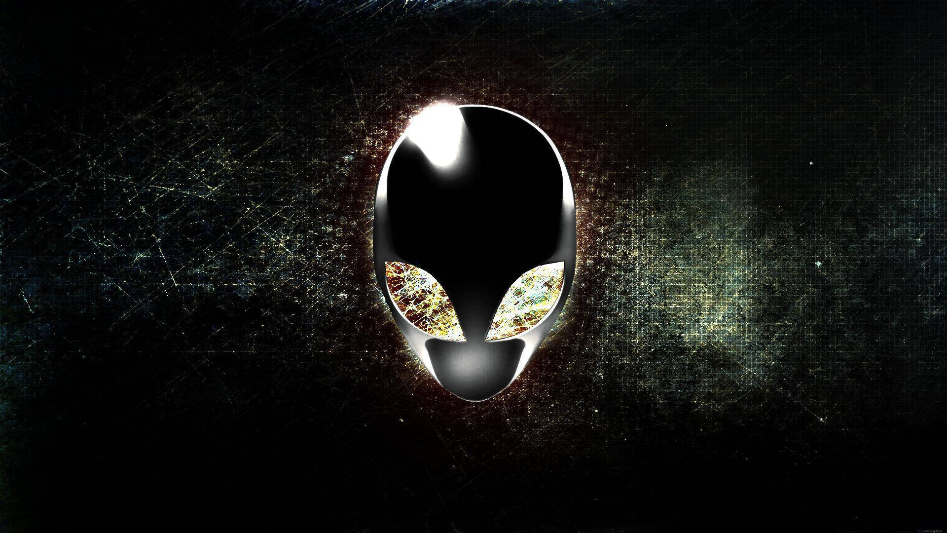 Unleash the power of gaming with Alienware Wallpaper — A glowing alien head logo with glittering eyes centered on a dark scratched metallic background.