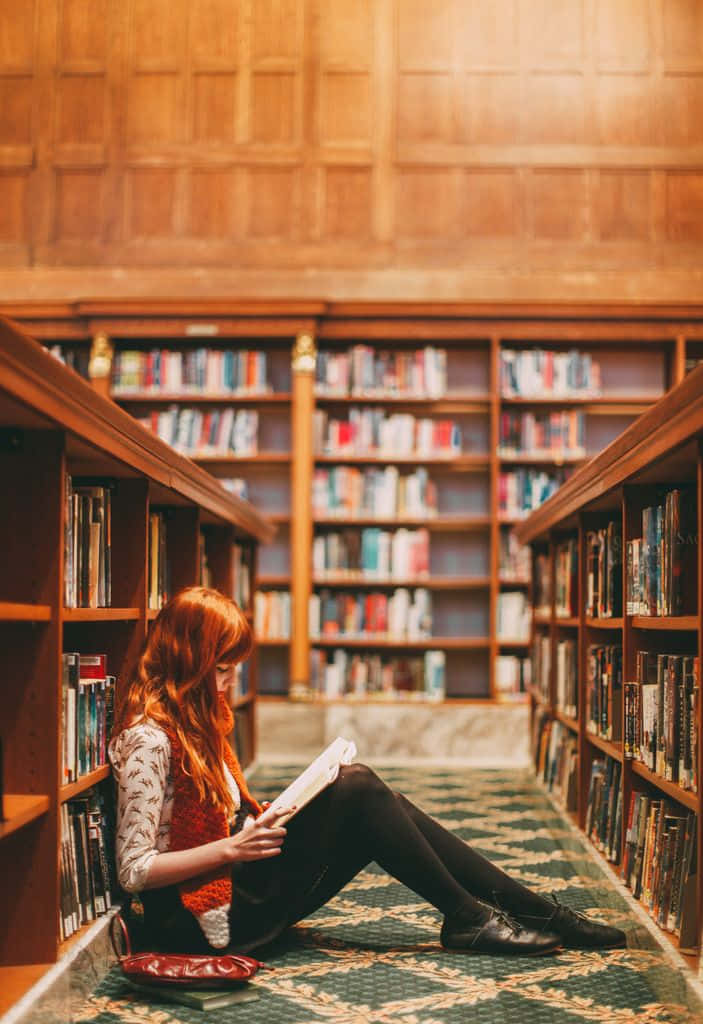 Imagemde Uma Garota Sentada Dentro De Uma Biblioteca.