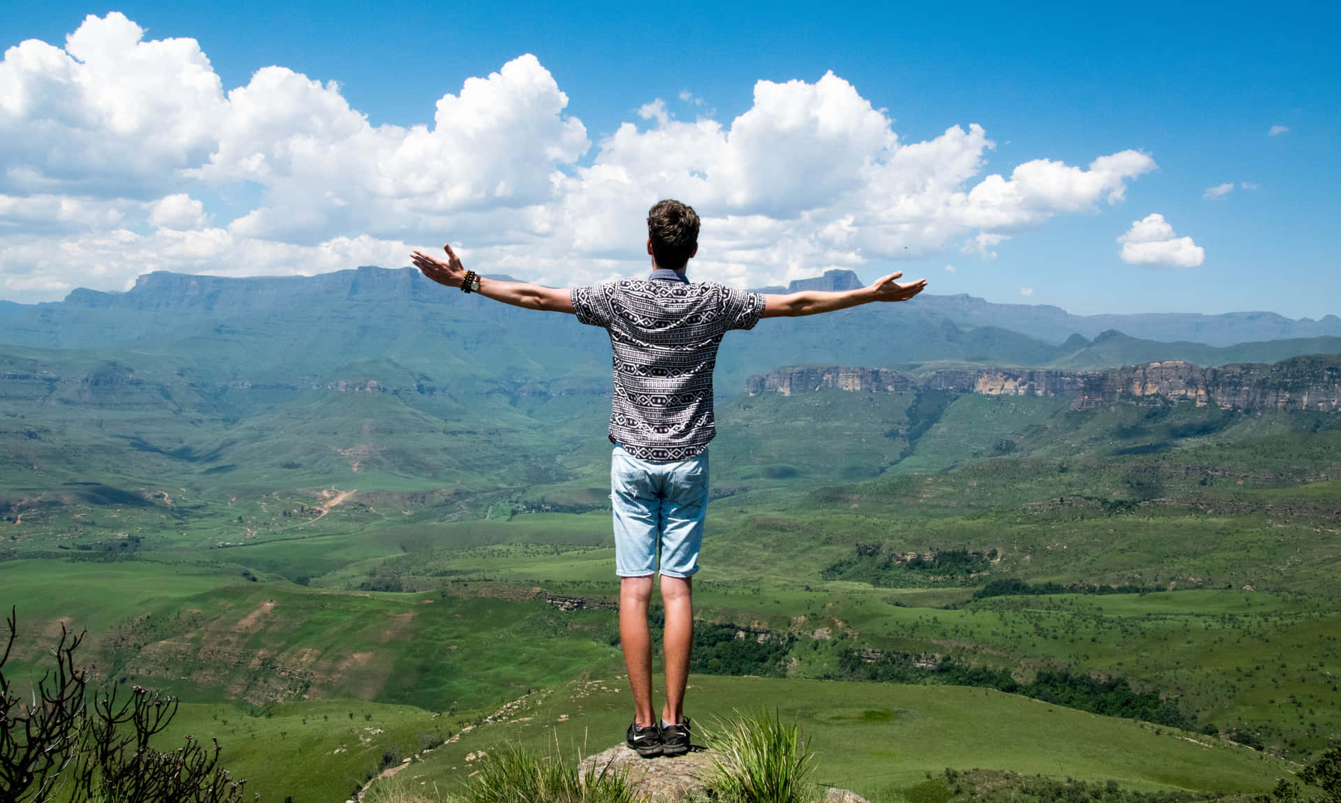 A Man Standing On Top Of A Mountain With His Arms Outstretched