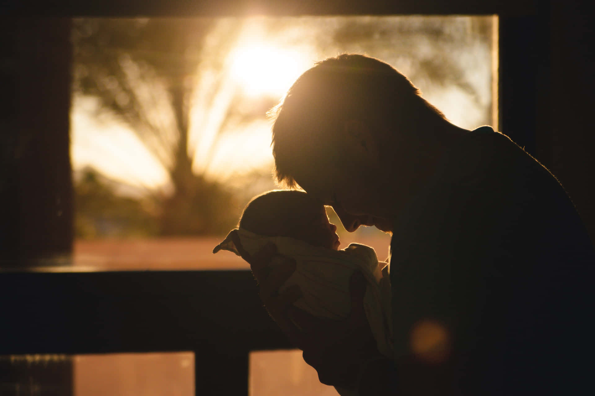 A Man Holding His Newborn Baby In Front Of A Window