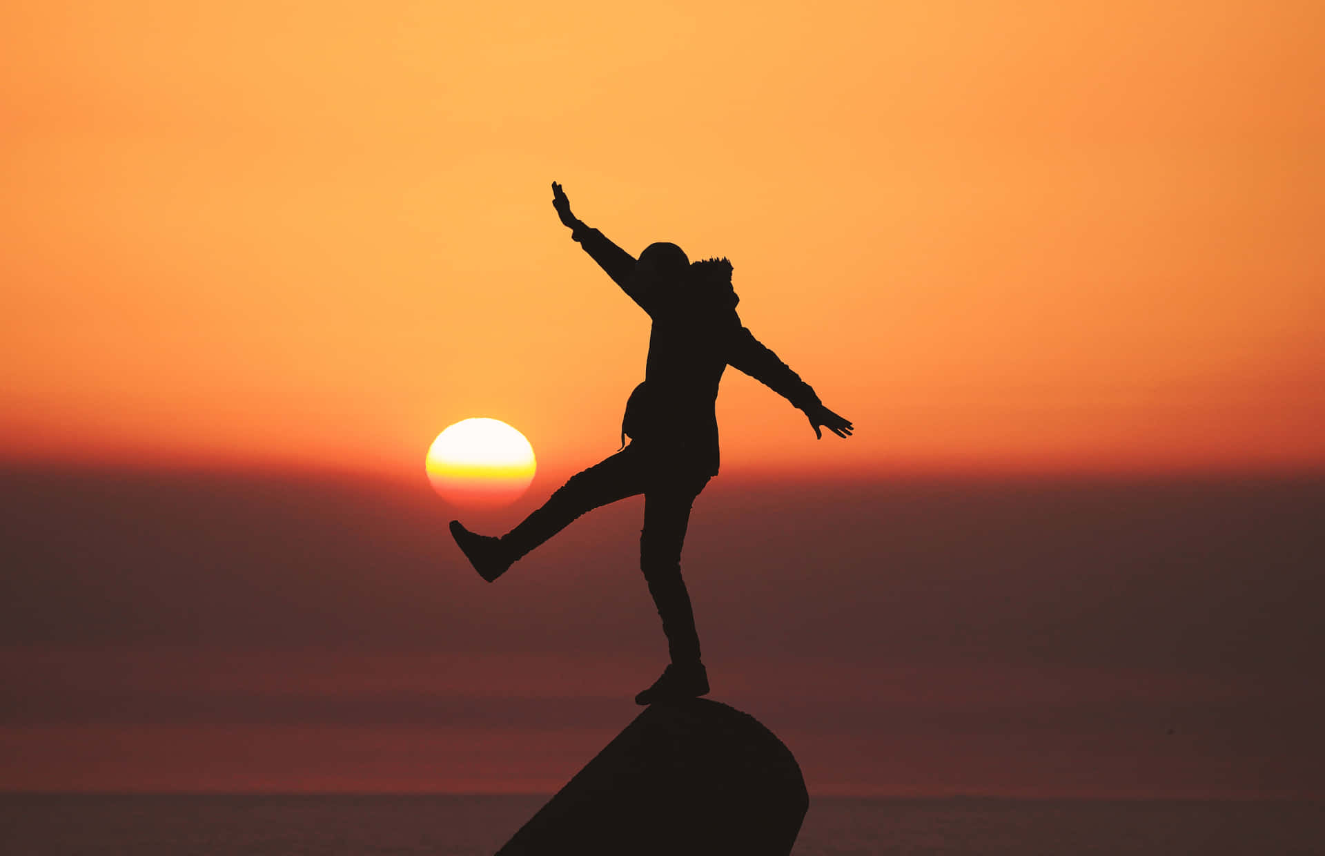 Silhouette Of A Person Jumping On A Rock