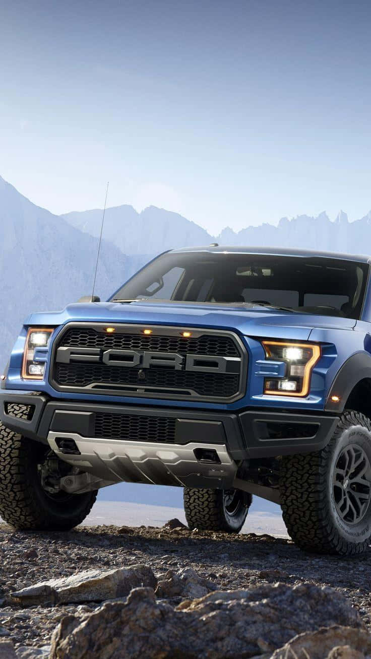 The Blue Ford F - 150 Raptor Is Parked On A Rocky Mountain Wallpaper