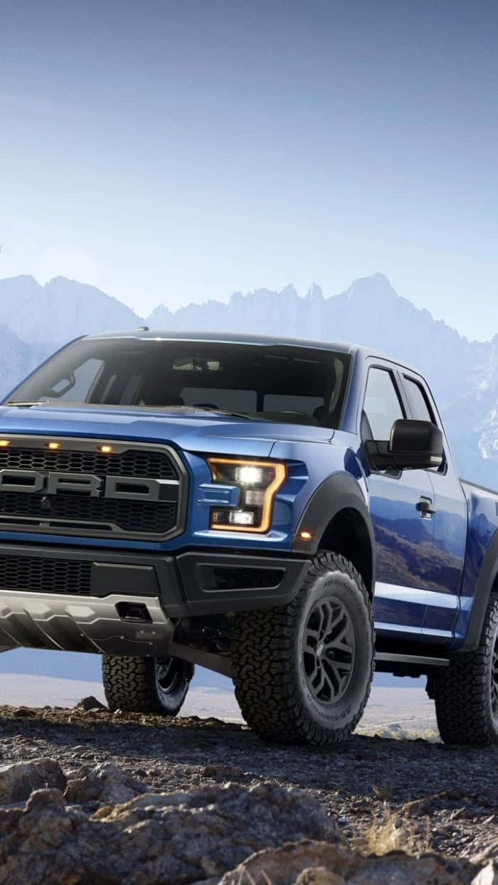 The Blue Ford F - 150 Raptor Is Parked On A Rocky Mountain Wallpaper