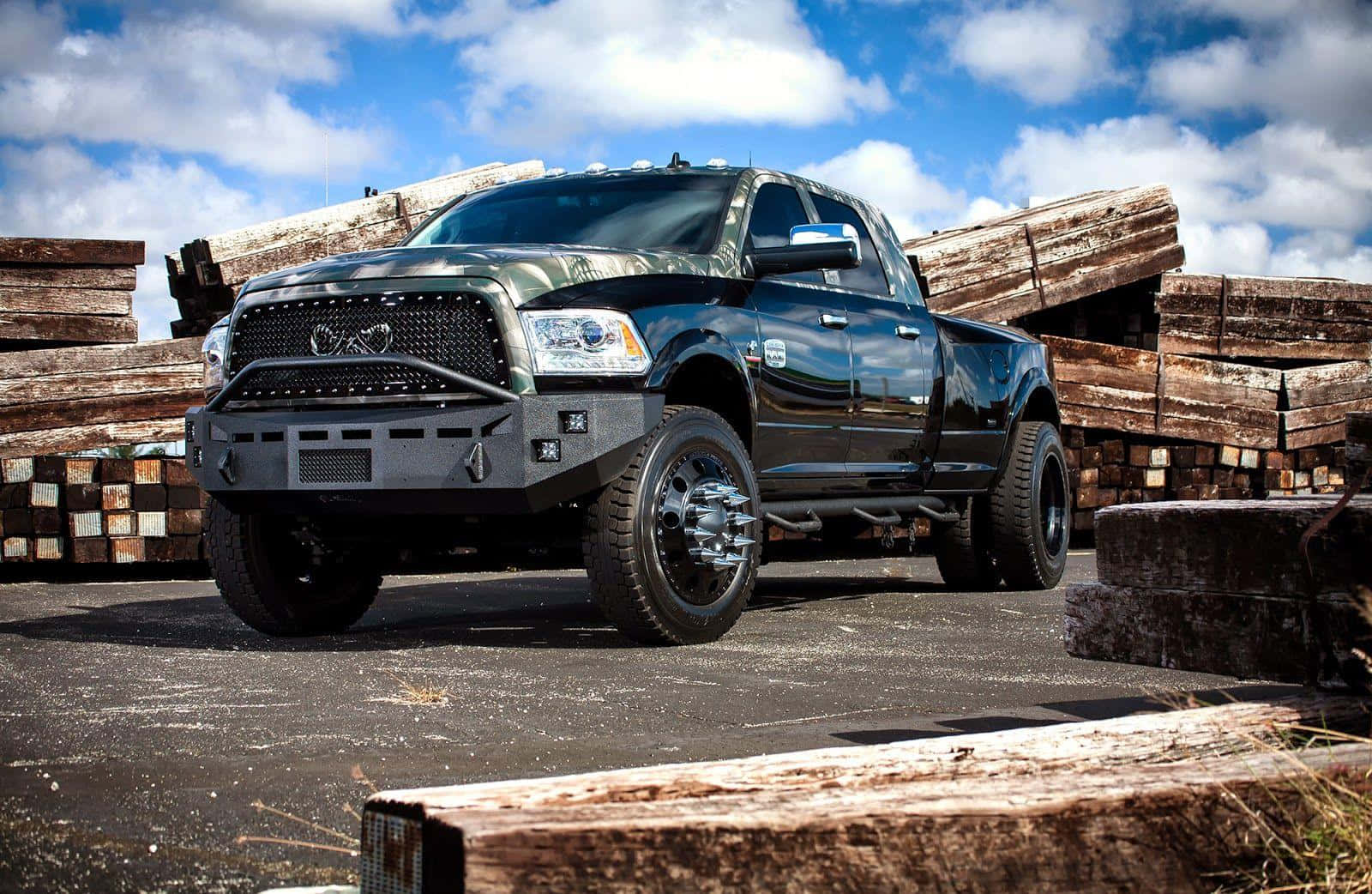 A Black Truck Parked In Front Of Logs Wallpaper