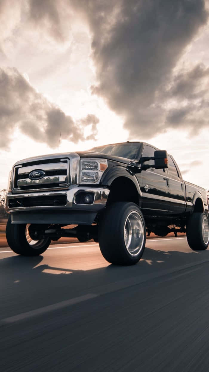 A Black Ford Super Duty Truck Driving Down The Road Wallpaper