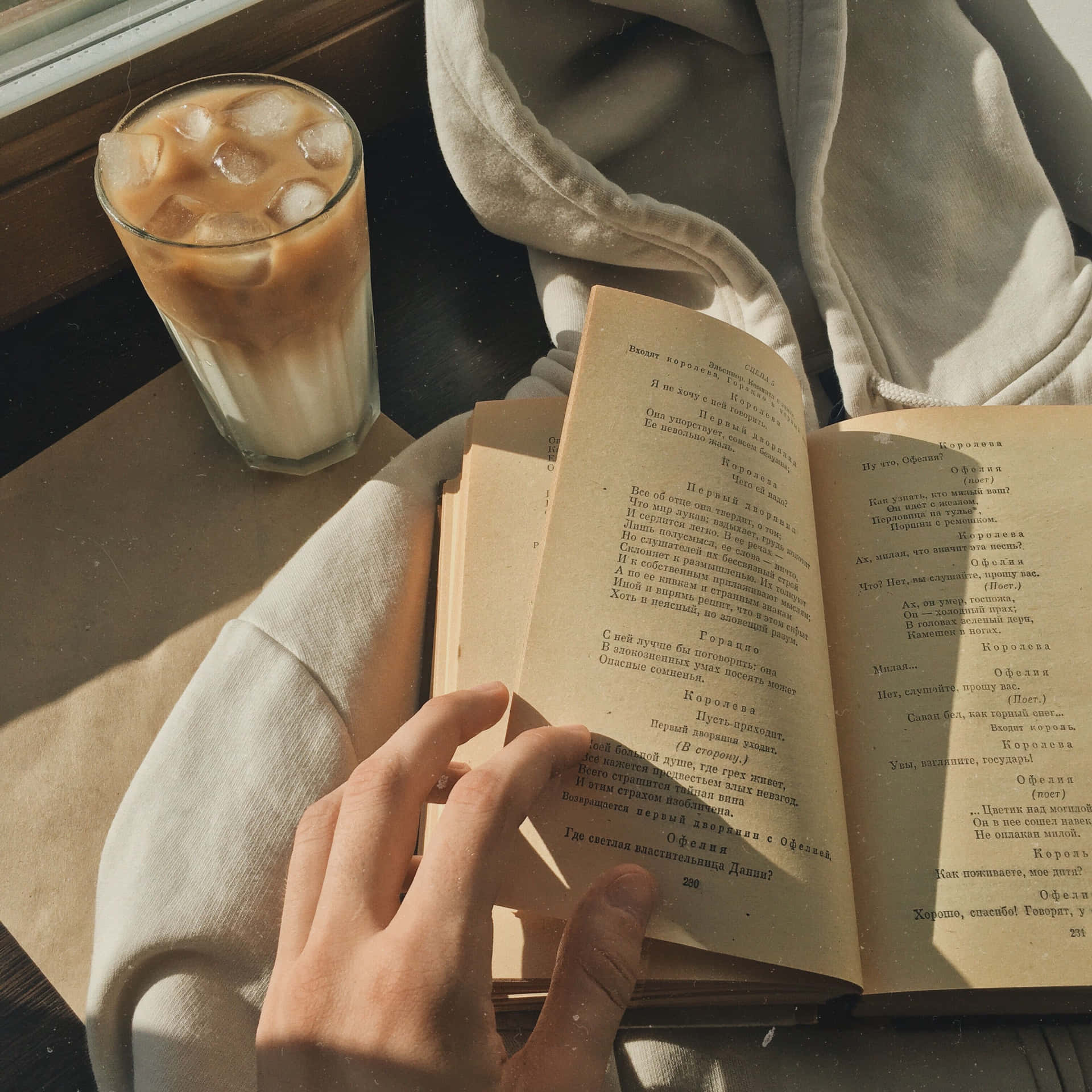 A Person Reading A Book With A Cup Of Coffee