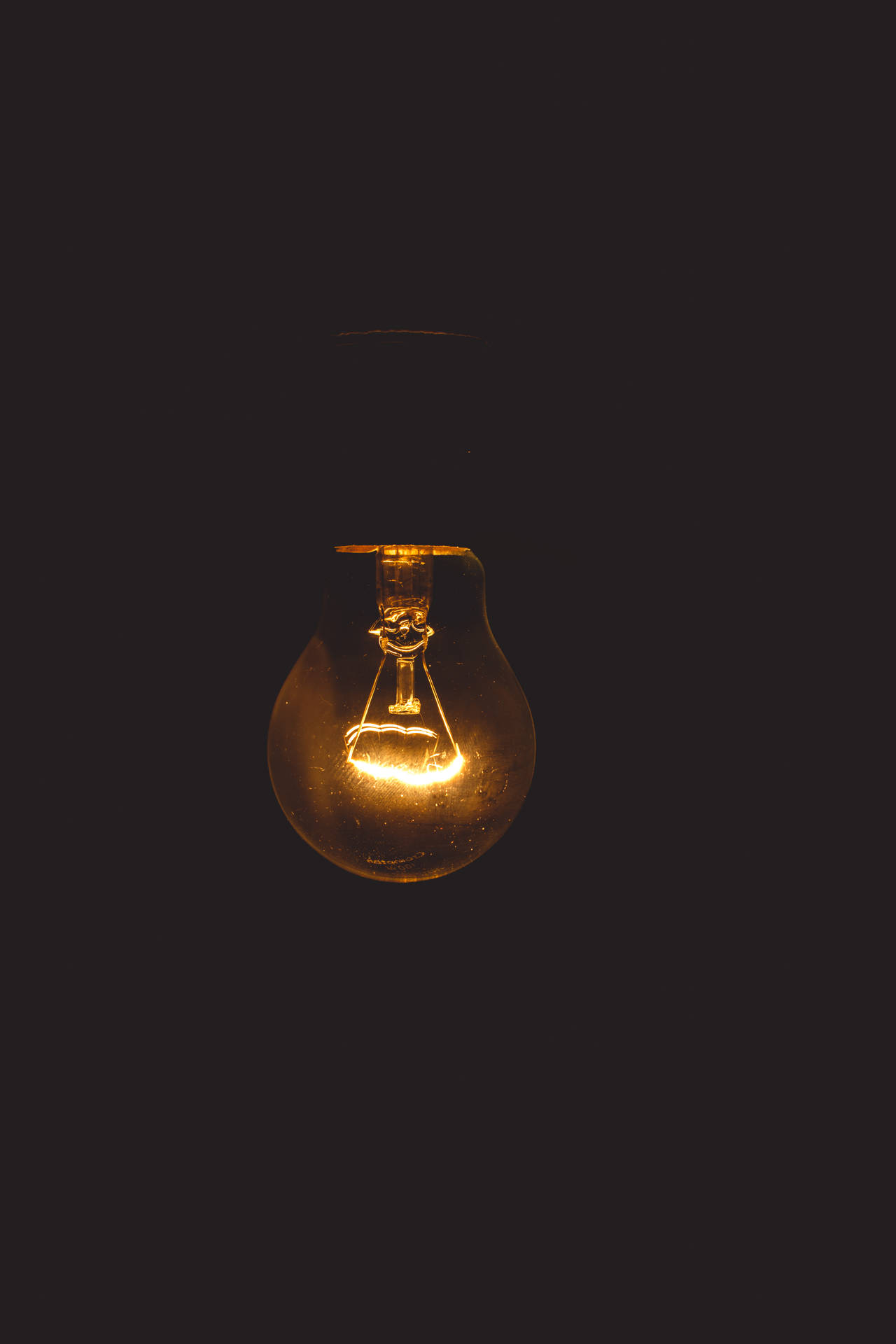 Glowing Light Bulb in Darkness - Symbol of Wisdom Wallpaper