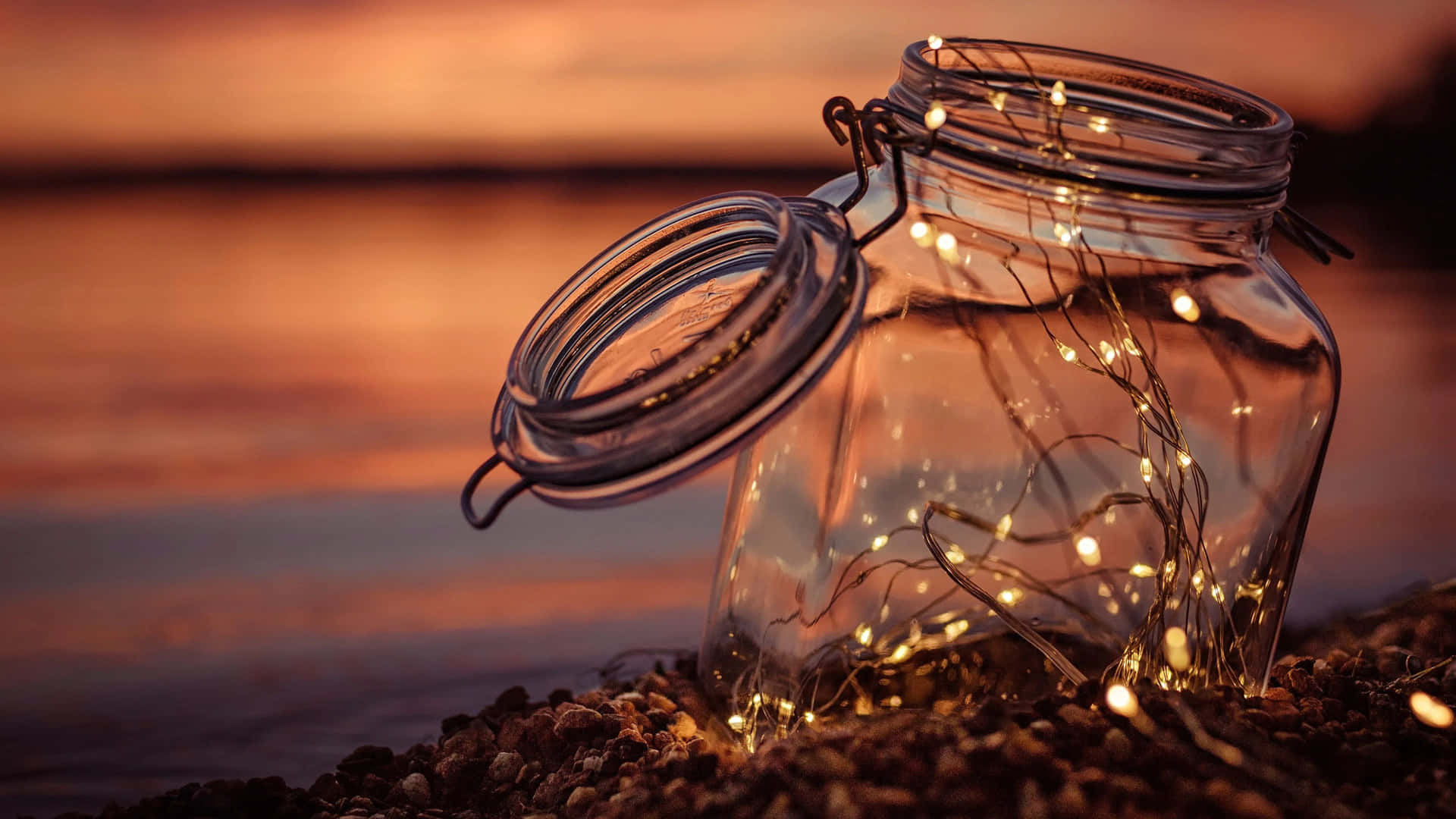 a glass jar with lights on it sitting on the shore