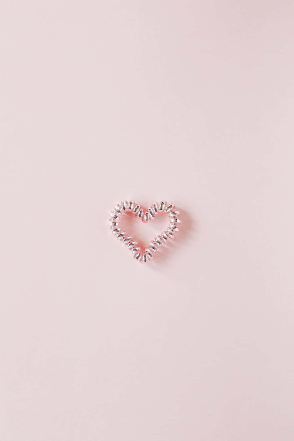 A Heart Shaped Hair Clip On A Pink Background Wallpaper