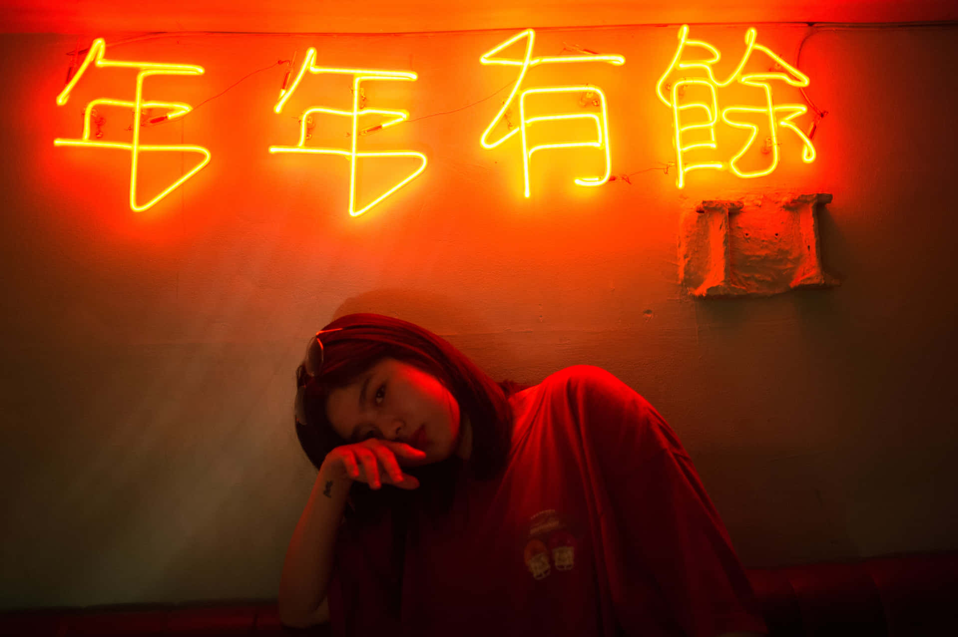 A Woman Is Laying Down In Front Of A Neon Sign Wallpaper