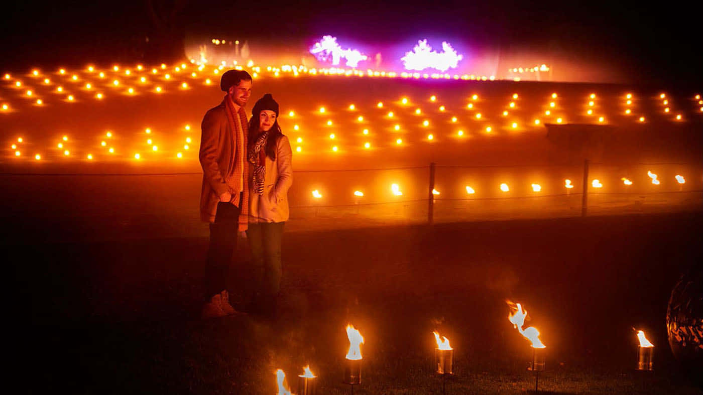 A Couple Standing In Front Of A Field Of Candles