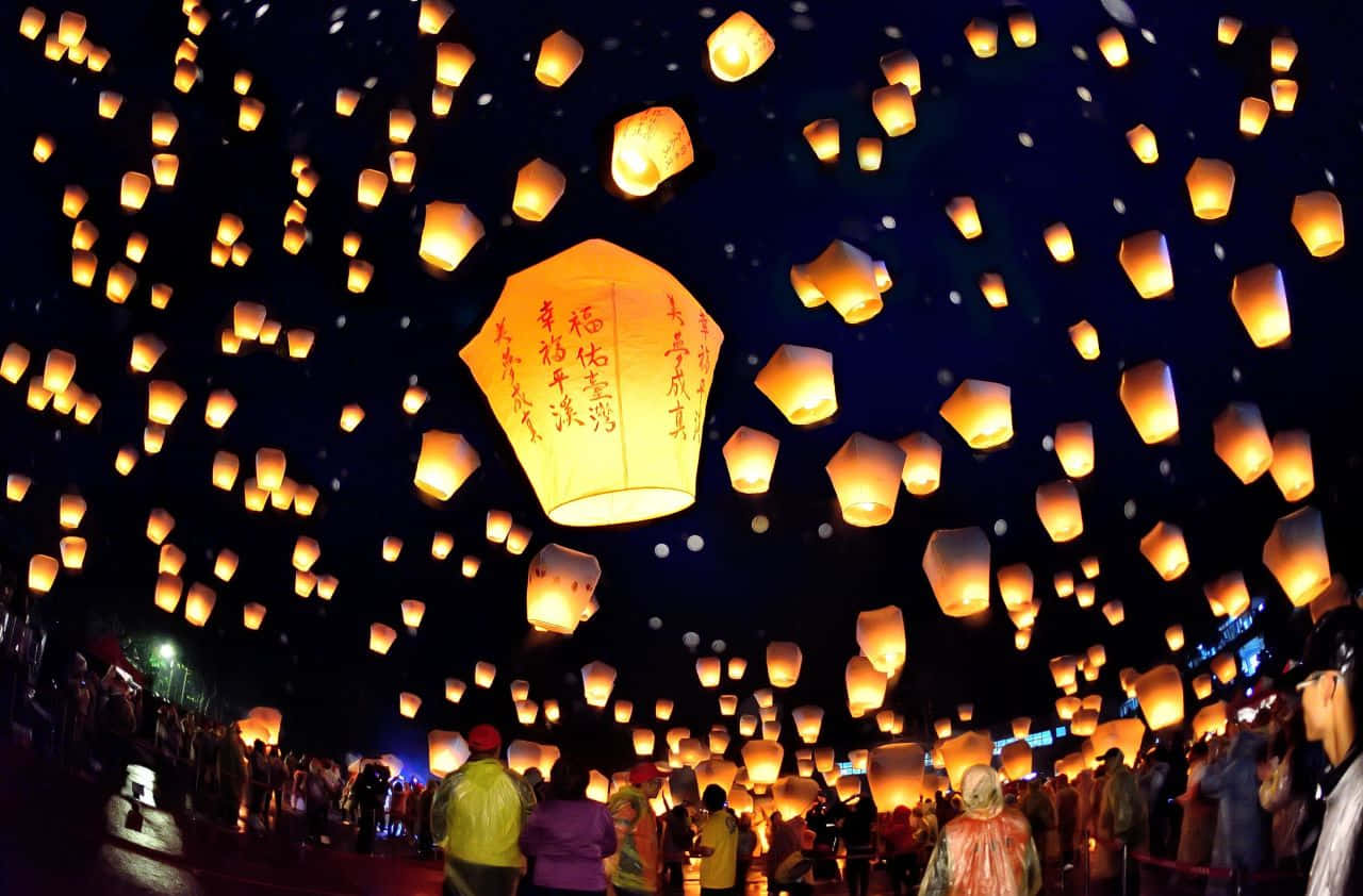 A Group Of People Are Flying Lanterns In The Sky