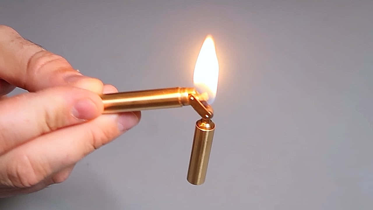 A Person Holding A Lighter With A Gold Tip