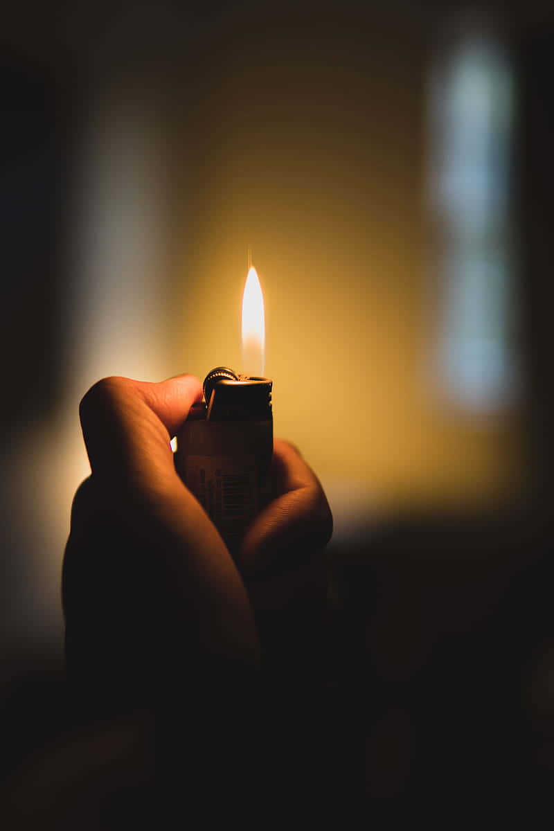 A Person Holding A Lighter In The Dark
