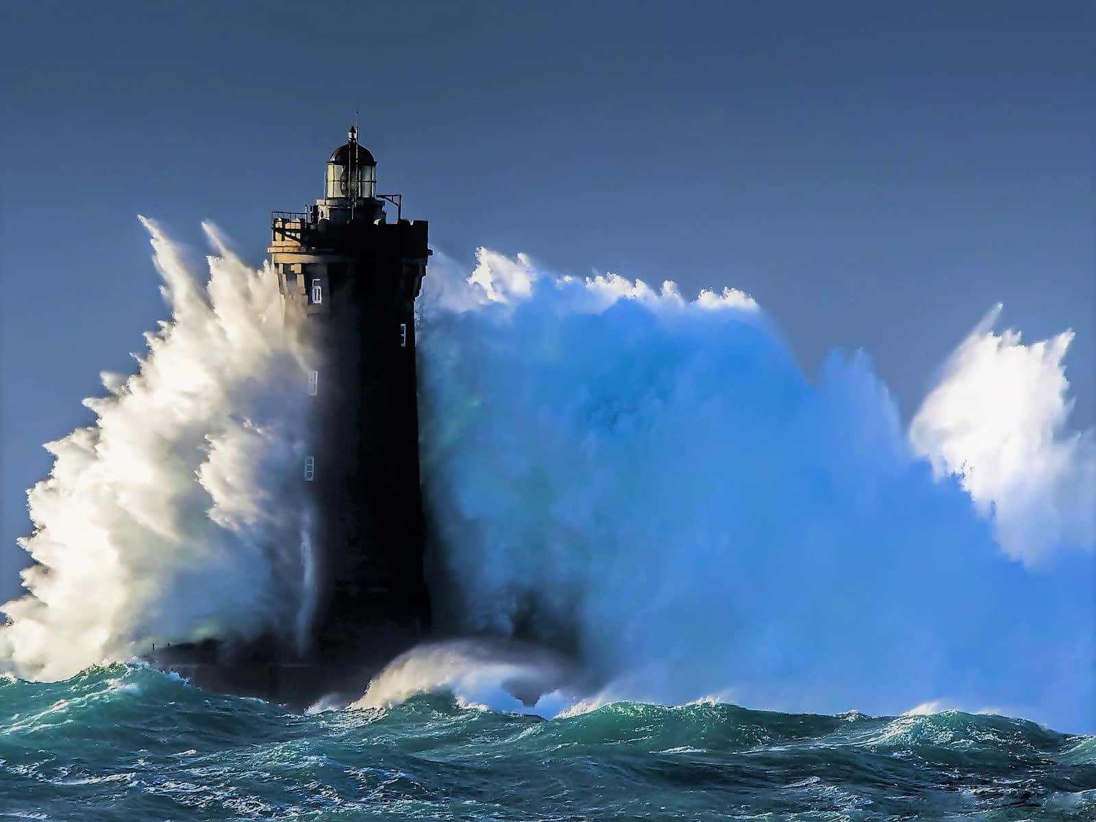 A Lighthouse Is Crashing Into A Large Wave