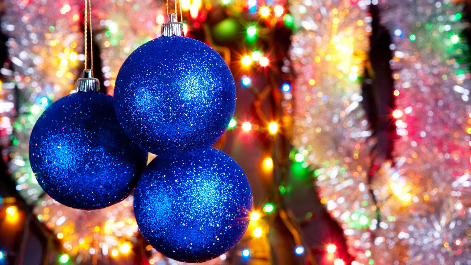 Tre blå julekugler henkastet fra en snor af lys