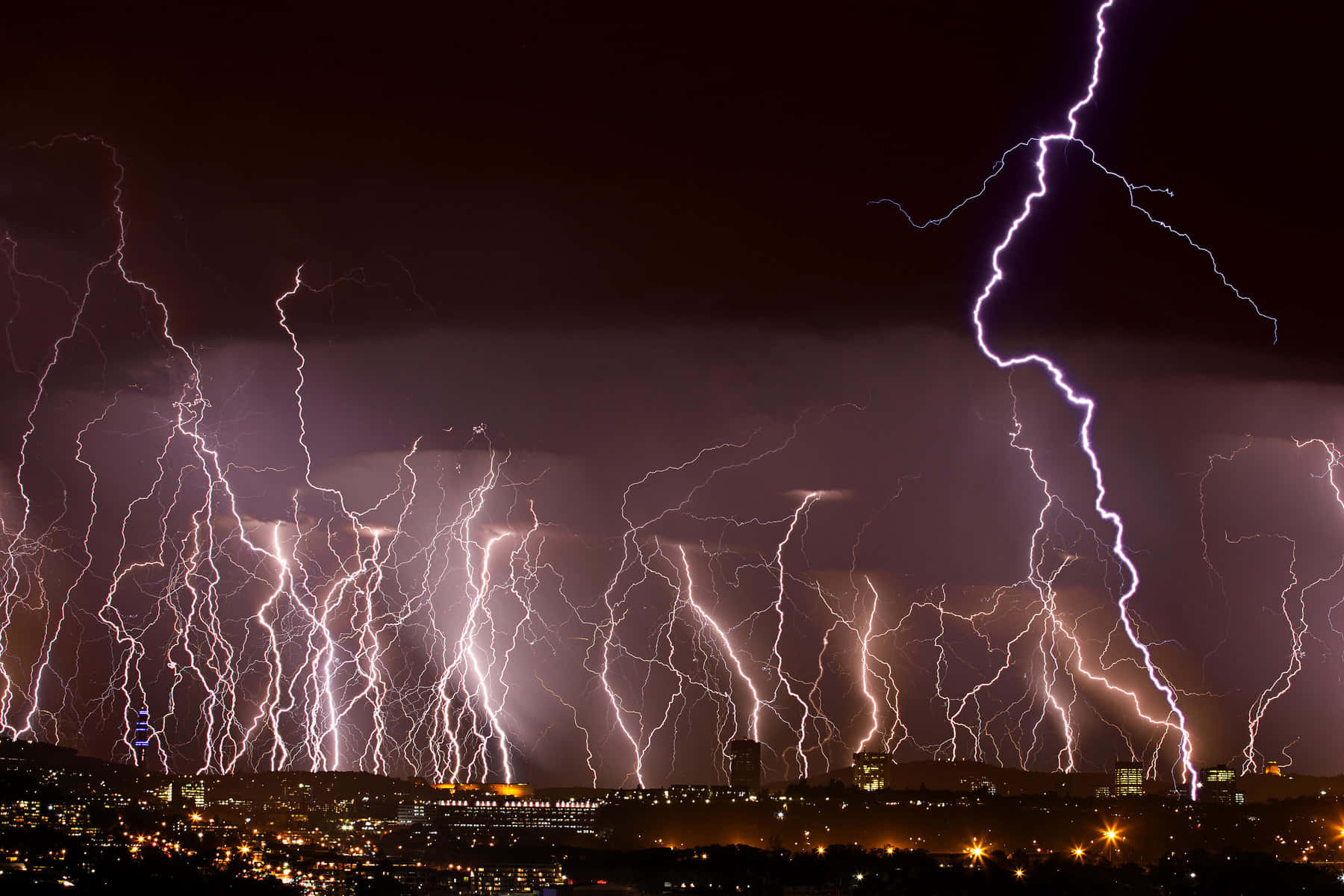 An illuminating lightning bolt shoots across a night sky.