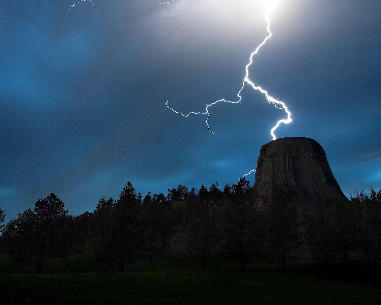 A powerful lightning strike in the background against a majestic plateau Wallpaper