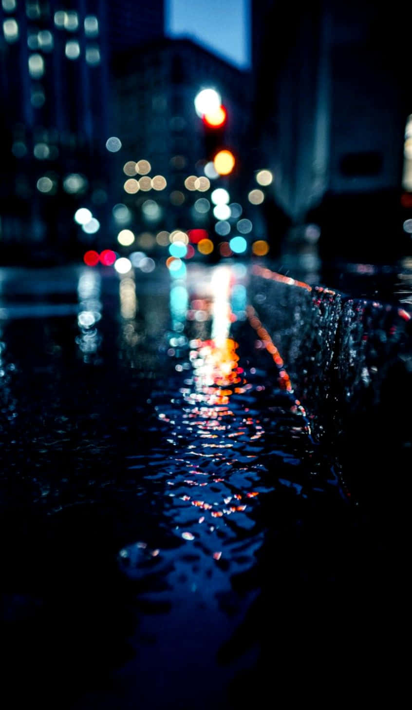 A vibrant display of city lights reflected in rain-soaked streets at night. Wallpaper