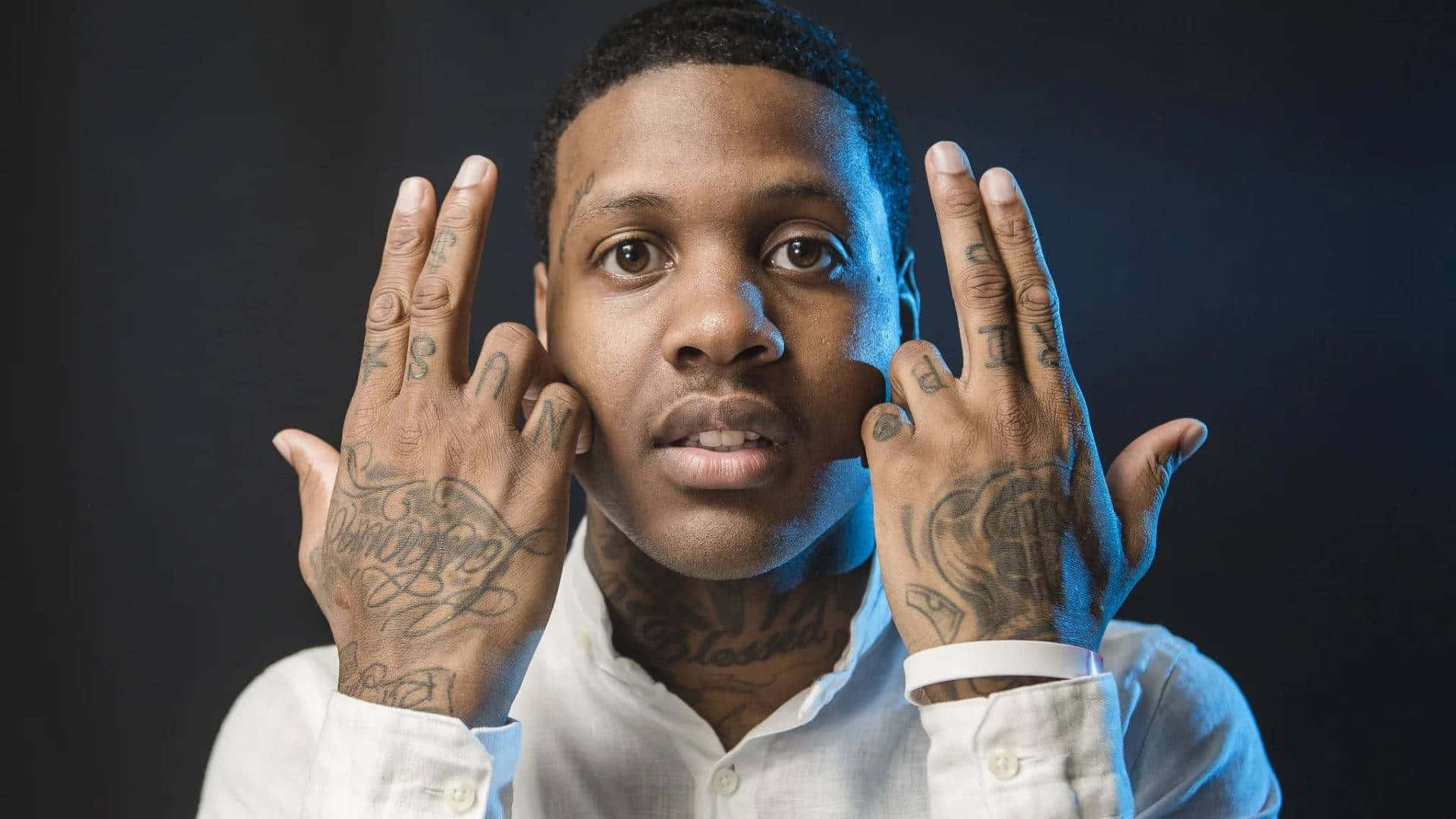 Lil Durk posing in a stylish outfit on a city rooftop