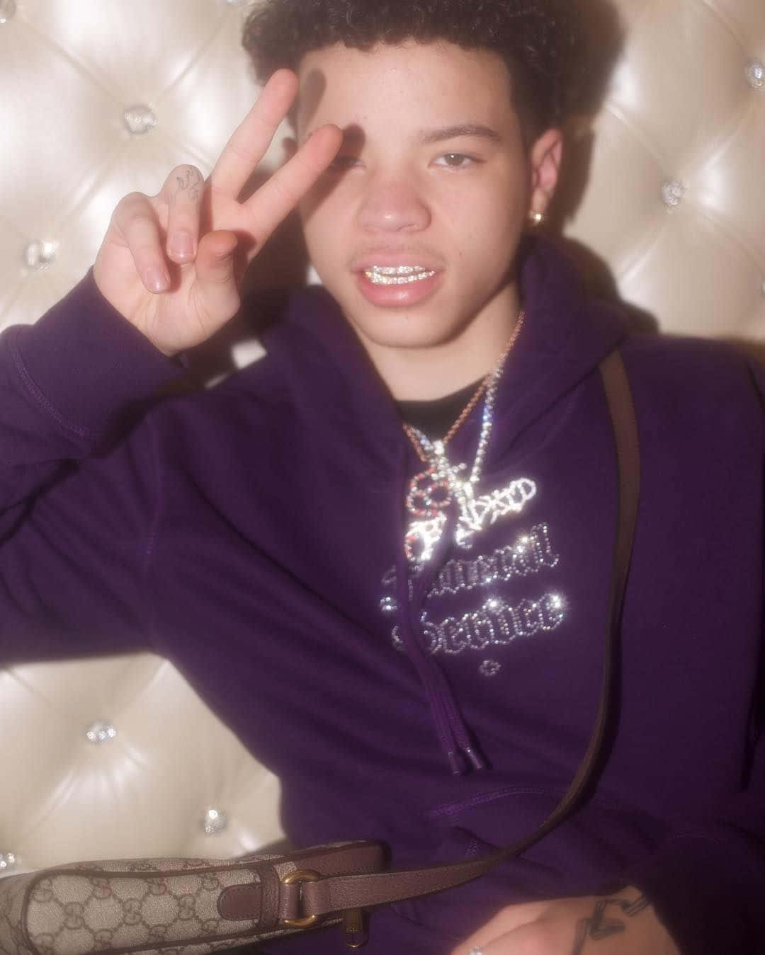 A Young Man Wearing A Purple Hoodie And A Purse Wallpaper
