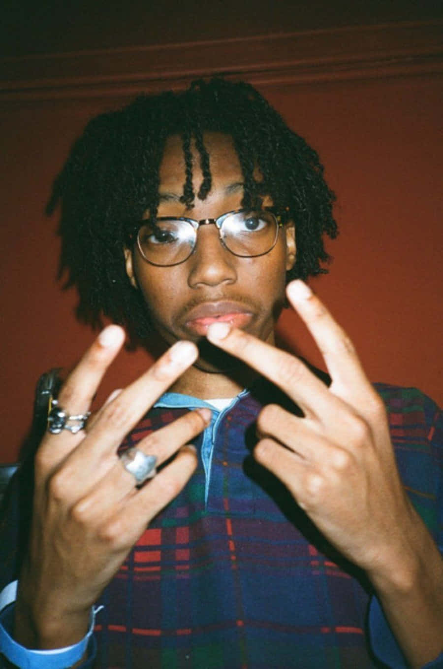 A Man With Glasses And Dreadlocks Making A Finger Gesture Wallpaper