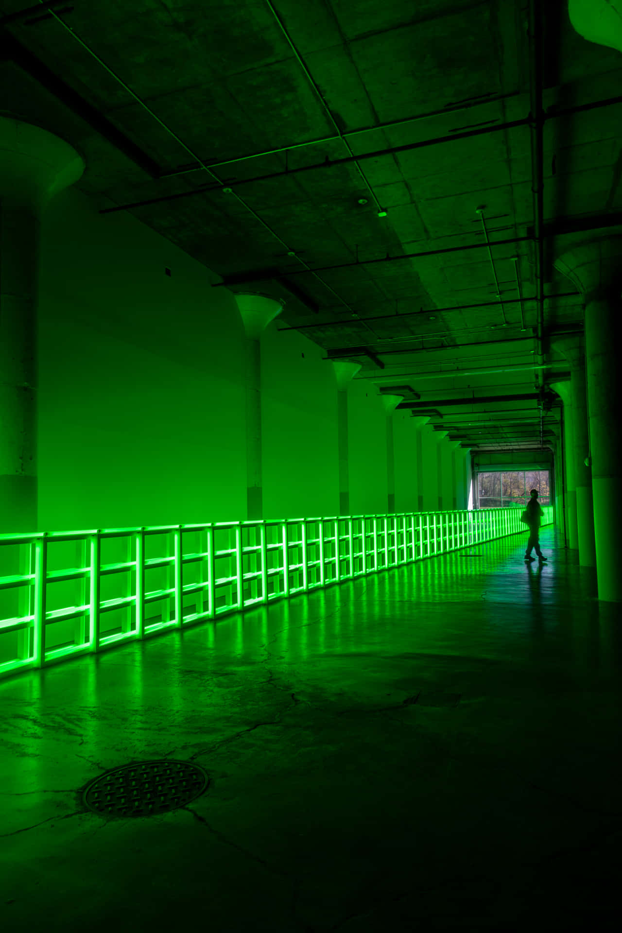 En person, der går ned ad et grønt oplyst tunnel. Wallpaper