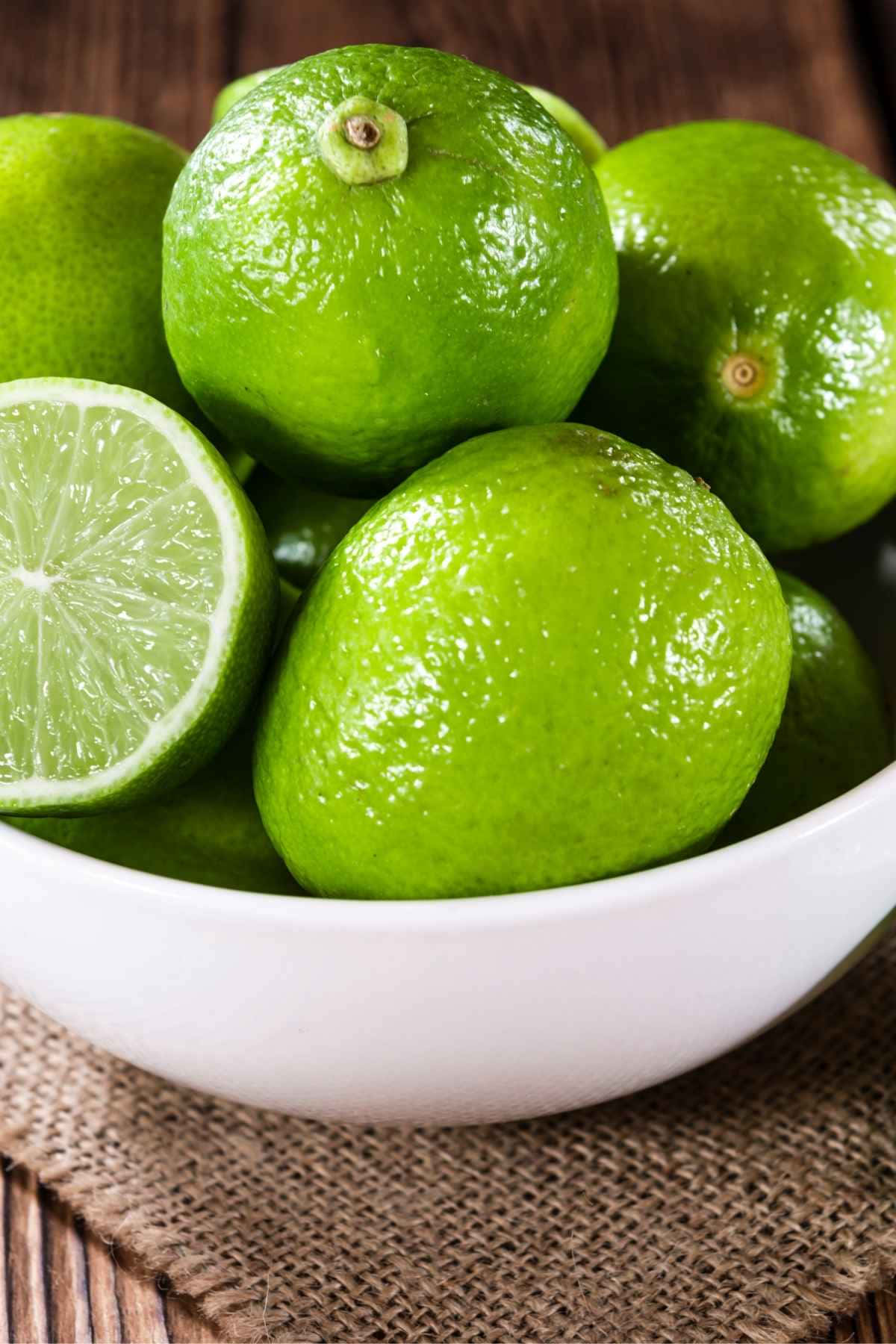Limes In A White Bowl On A Wooden Table
