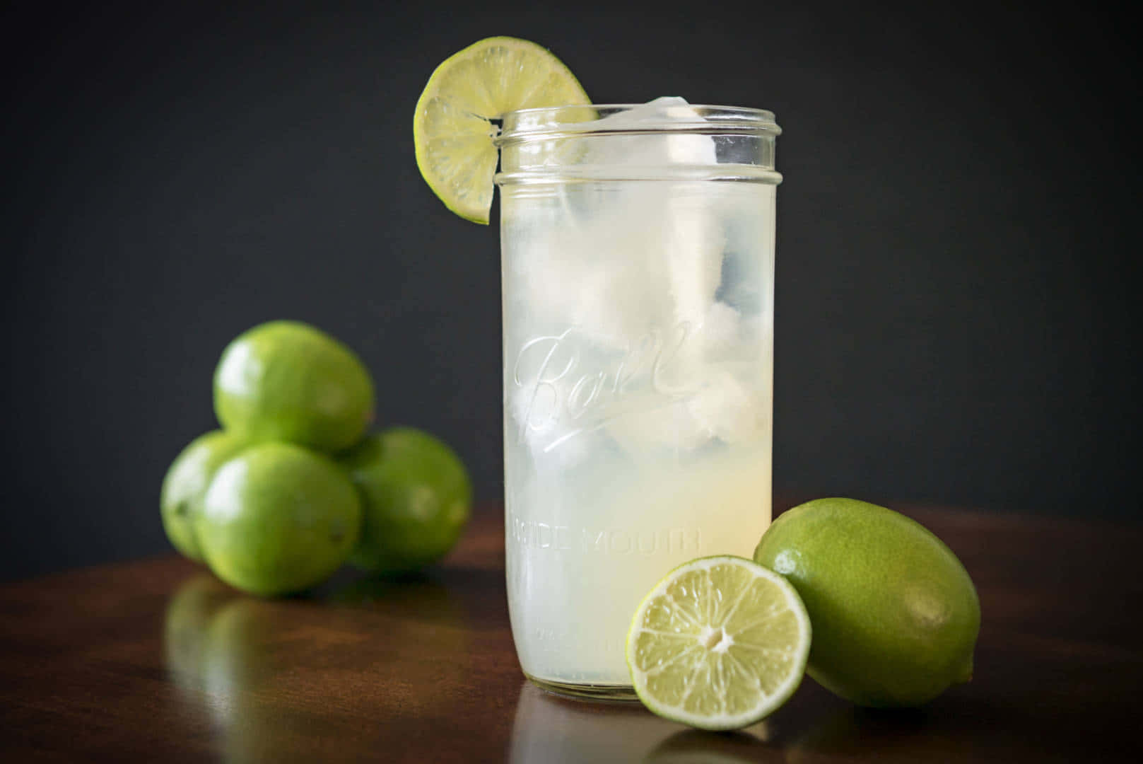 A Glass Of Lime Juice With Ice And Limes