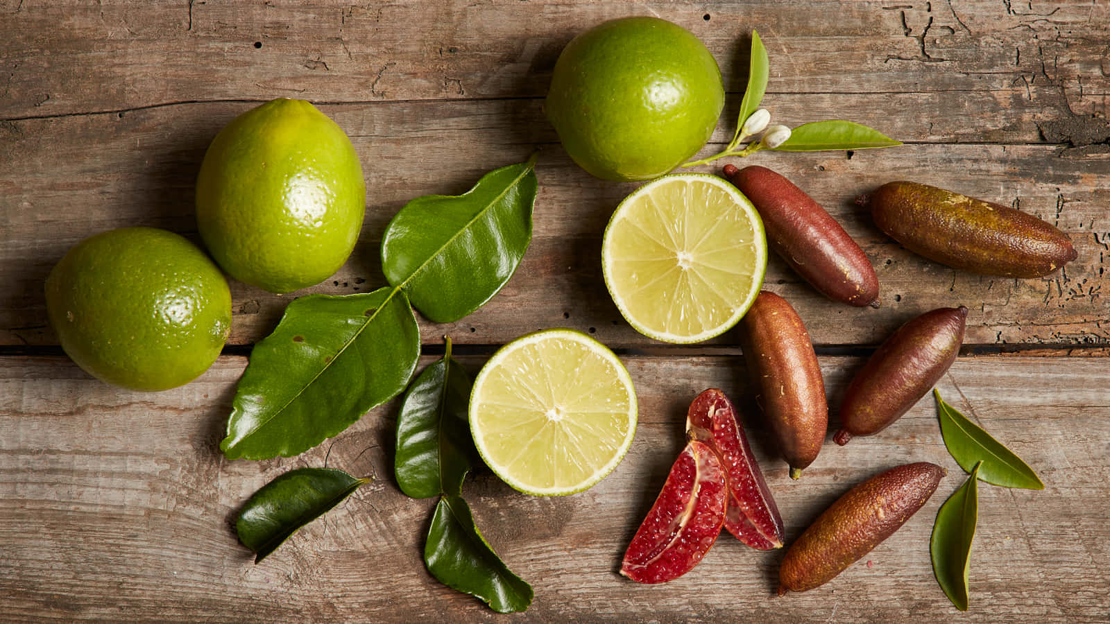 A Bunch Of Limes And Other Fruit On A Wooden Table
