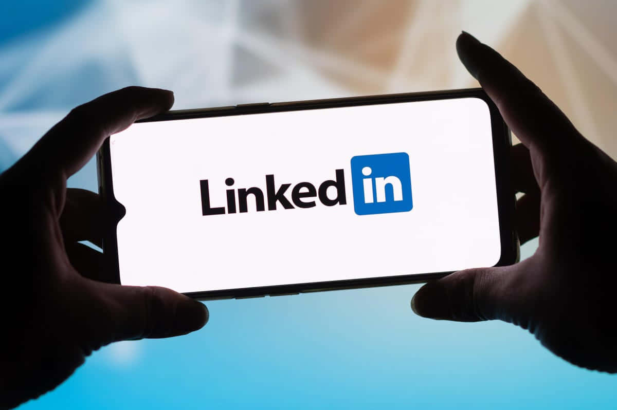 A Person Holding Up A Phone With The Linkedin Logo On It