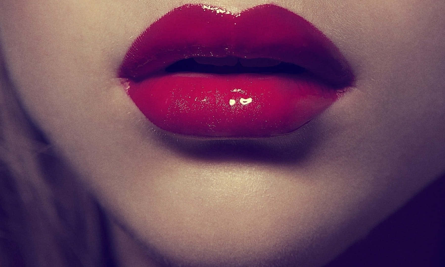 Glossy red lipstick on a close-up of luscious lips