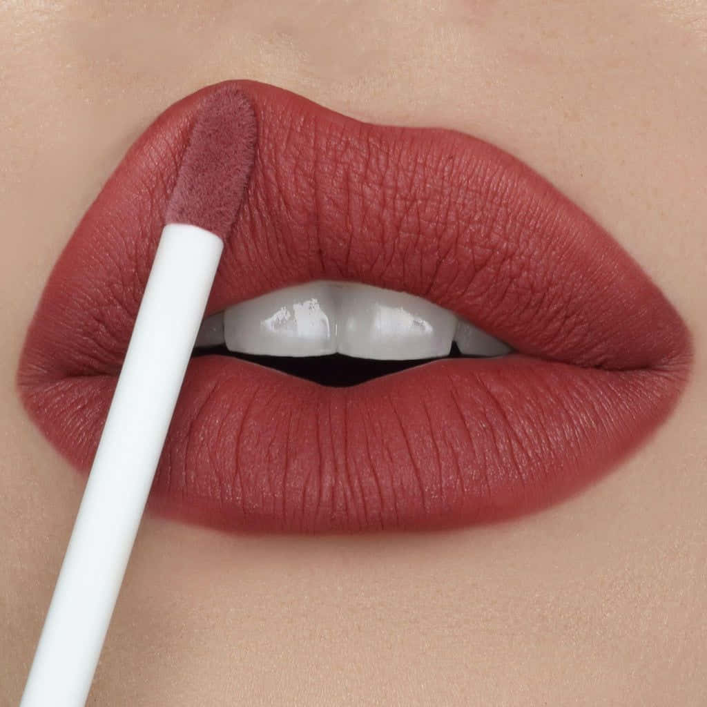A Woman Is Holding A Lipstick With A White Brush