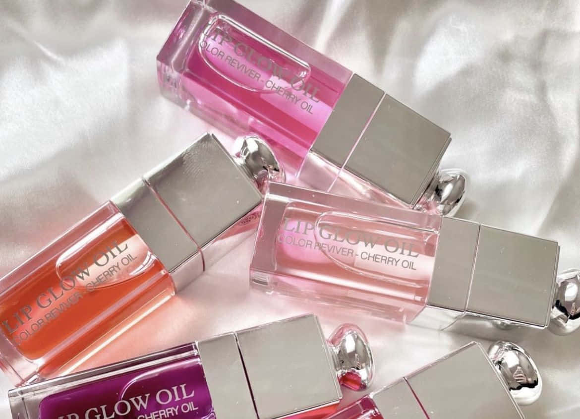 A Group Of Pink And Silver Bottles On A White Bed