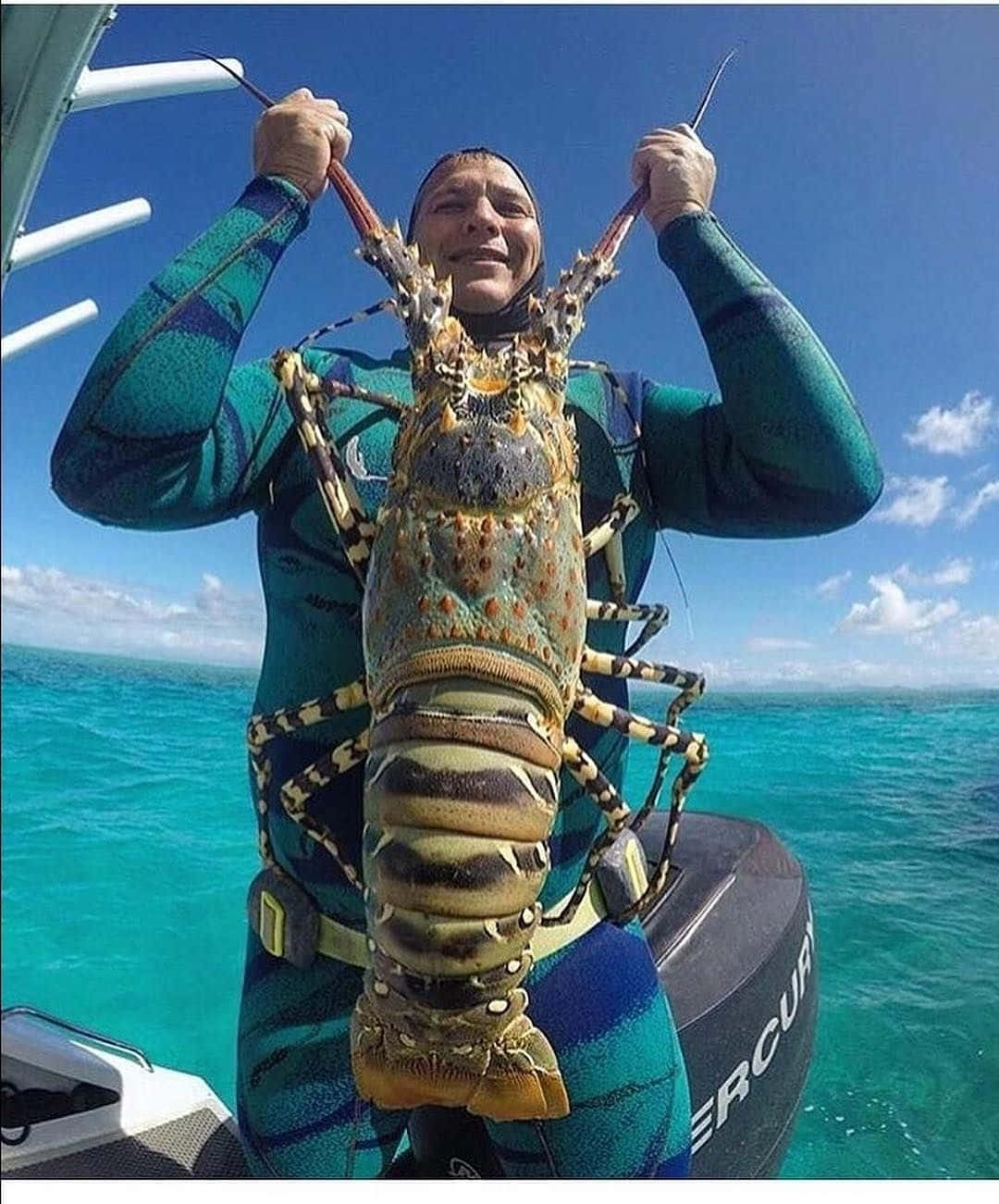A Man Holding Up A Lobster In The Ocean