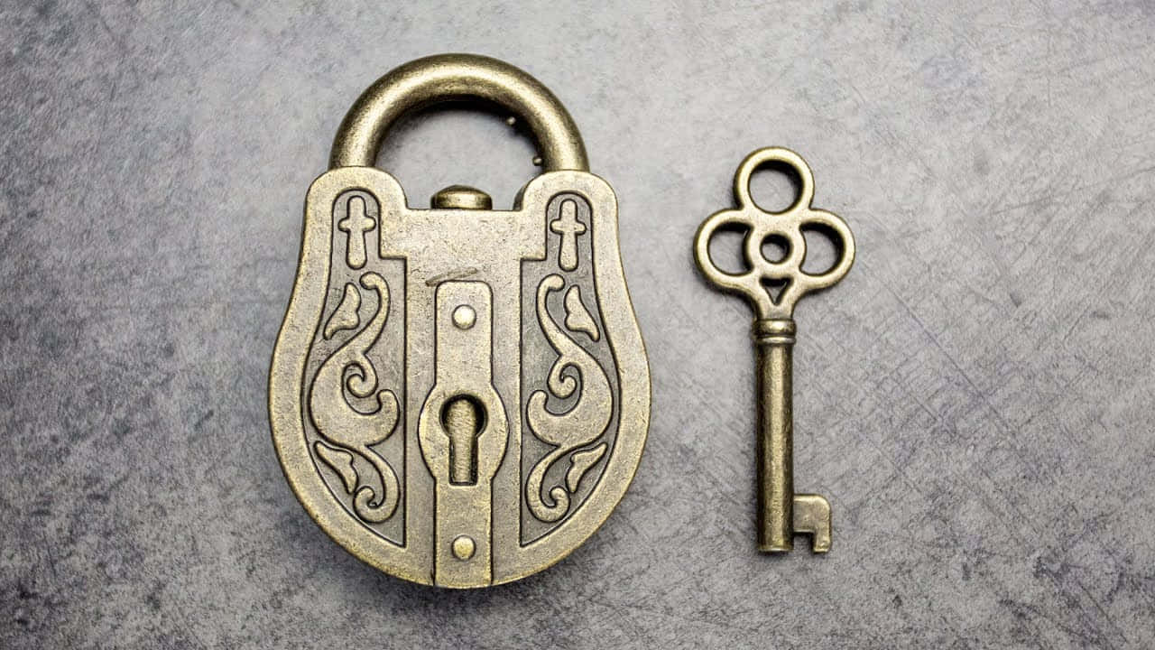 Antique Brass Padlock And Key On A Grey Background