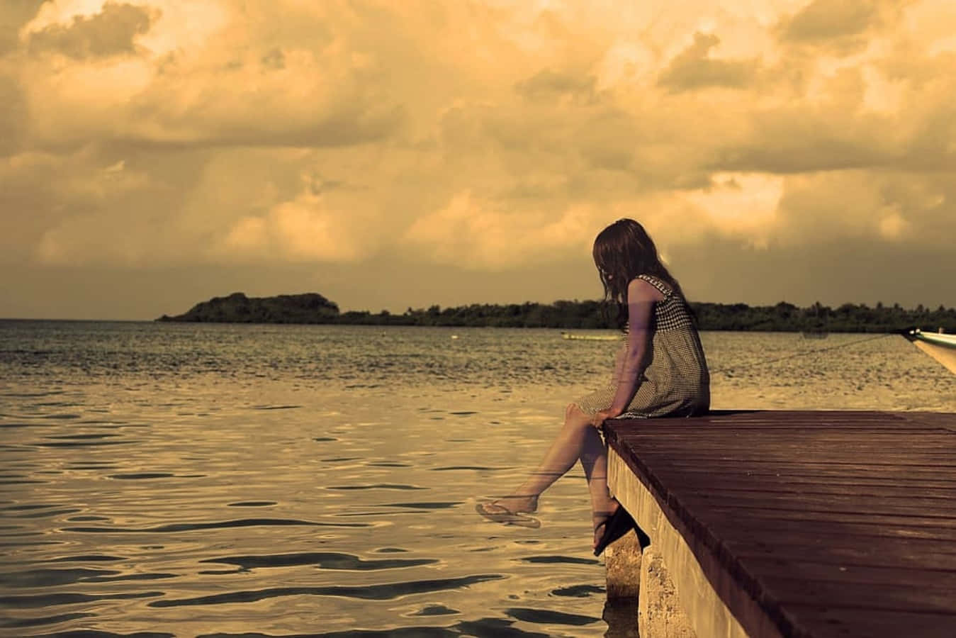 A Girl Sitting On A Dock Looking At The Water