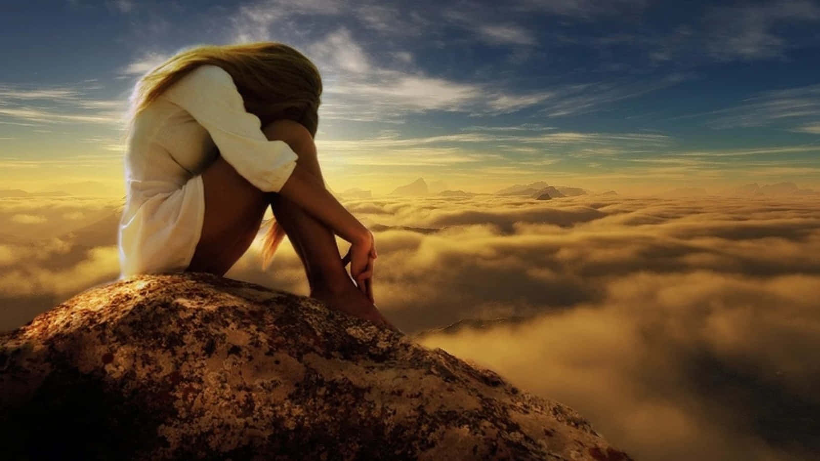 A Woman Sitting On Top Of A Mountain With Clouds In The Background